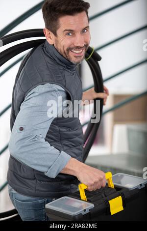 Porträt eines selbstbewussten Arbeiters, der einen Werkzeugkasten in der Hand hält Stockfoto