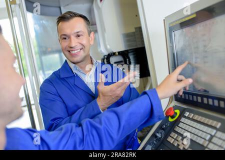 Zwei Männer, die auf den Computerbildschirm zeigen und lachen Stockfoto