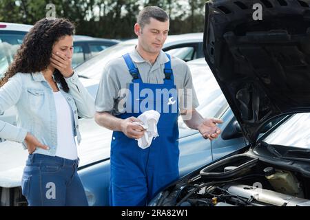 Der Mechaniker erklärt dem Kunden das Problem mit dem Fahrzeugmotor Stockfoto