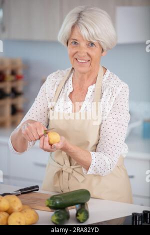 Seniorin bereitet Essen in der Küche zu Stockfoto