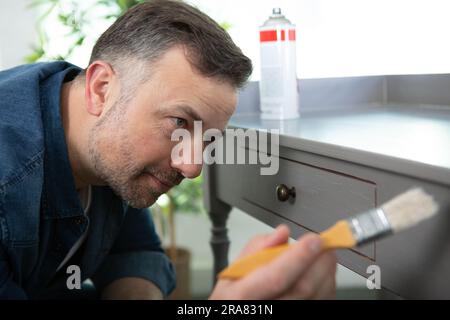 Ein Mann lackiert Holzmöbel Stockfoto