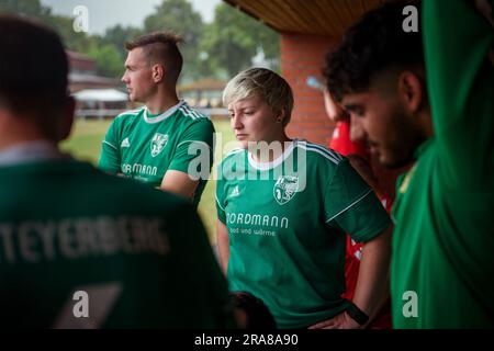 PRODUKTION – 01. Juli 2023, Niedersachsen, Deblinghausen: Amateurfußballspielerin Celine Saßnick (M) steht mit ihren Teamkollegen aus dem Team der TuS Steyerberg am Rande des lokalen Fußballfelds in Deblinghausen vor dem Spiel gegen TV Wellie. Saßnick, 28, tritt seit 17 Jahren mit TuS Steyerberg im Bezirk Nienburg/Weser. Sie ist derzeit Stürmer für die dritte Mannschaft in der dritten Distriktabteilung. Manchmal hilft sie auch im zweiten Team einer der obigen Abteilungen. Das ist ihr jedoch erst seit Dezember möglich. Seitdem sind es auch die Frauen in Niedersachsen Stockfoto