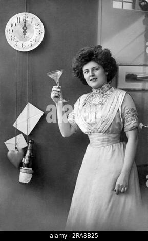 Dänemark: 1912. Eine Frau neben einer Uhr mit einem Steinherz und einer Champagnerflasche für Pendelgewichte erhebt um Mitternacht ein Champagnerglas in einem Toast. Stockfoto