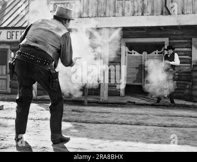 Hollywood, Kalifornien: ca. 1950 der gute Cowboy (Lichthut) scheint in dieser Western-Filmszene vor den Türen des Saloons die Anziehungskraft auf den bösen Cowboy (dunkler Hut) zu ziehen. Stockfoto