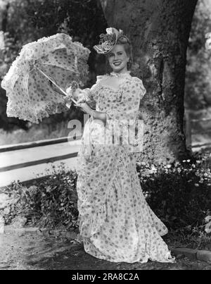 Vereinigte Staaten: ca. 1940 eine attraktive junge Frau in viktorianischem Kleid mit einem Sonnenschirm. Stockfoto