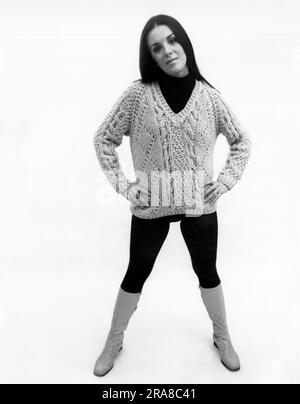 Vereinigte Staaten: c. 1970 Eine junge, hippe Frau modelliert kälberhohe Stiefel und einen Skistiefel, der über einem Strumpf getragen wird. Stockfoto