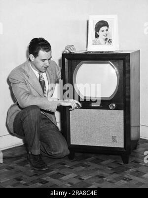 USA: ca. 1955 Ein Mann, der sein Motorola-Fernsehgerät anpasst. Stockfoto