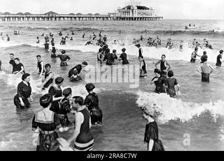 Atlantic City, New Jersey: 4. Juli 1911 Bathers in den Gewässern des Atlantiks mit dem Steel Pier im Hintergrund. Stockfoto