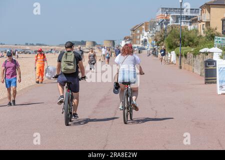 Zwei Radfahrer fahren entlang einer geschäftigen Strandpromenade Stockfoto