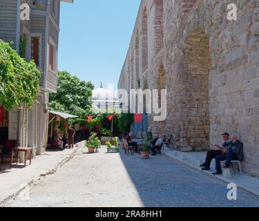 Einheimische sitzen im Schatten auf einer Straße neben dem Aquädukt von Valens, einem römischen Aquädukt in Istanbul, Türkei Stockfoto