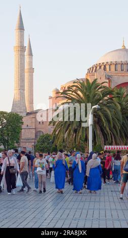 Drei muslimische Frauen in blauer Kleidung unter den Menschenmassen laufen an einem Sommerabend in Richtung Hagia Sophia Moschee. Istanbul, Türkei. Stockfoto