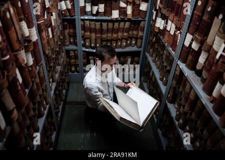 Laurence ward, Head of Digital Services bei den London Metropolitan Archives (LMA), zieht ein Buch aus dem Lager der größten historischen Archive in Großbritannien. Mit über 100km Büchern, Karten, Fotografien, Filmen und Dokumenten aus dem Jahr 1067, die in den Strong Rooms aufbewahrt werden, ist das LMA das wichtigste Archiv der lokalen Regierung für den Großraum London, einschließlich der City of London, und das größte County-Plattenbüro in Großbritannien. Foto: Dienstag, 27. Juni 2023. Stockfoto