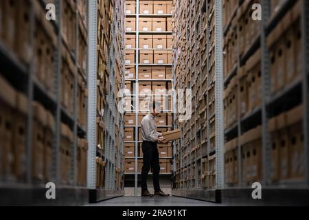 Laurence ward, Head of Digital Services bei den London Metropolitan Archives (LMA), zieht eine Box aus dem Lager der größten historischen Archive in Großbritannien. Mit über 100km Büchern, Karten, Fotografien, Filmen und Dokumenten aus dem Jahr 1067, die in den Strong Rooms aufbewahrt werden, ist das LMA das wichtigste Archiv der lokalen Regierung für den Großraum London, einschließlich der City of London, und das größte County-Plattenbüro in Großbritannien. Foto: Dienstag, 27. Juni 2023. Stockfoto