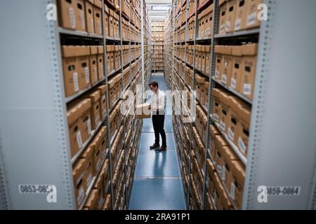 Laurence ward, Head of Digital Services bei den London Metropolitan Archives (LMA), zieht eine Box aus dem Lager der größten historischen Archive in Großbritannien. Mit über 100km Büchern, Karten, Fotografien, Filmen und Dokumenten aus dem Jahr 1067, die in den Strong Rooms aufbewahrt werden, ist das LMA das wichtigste Archiv der lokalen Regierung für den Großraum London, einschließlich der City of London, und das größte County-Plattenbüro in Großbritannien. Foto: Dienstag, 27. Juni 2023. Stockfoto