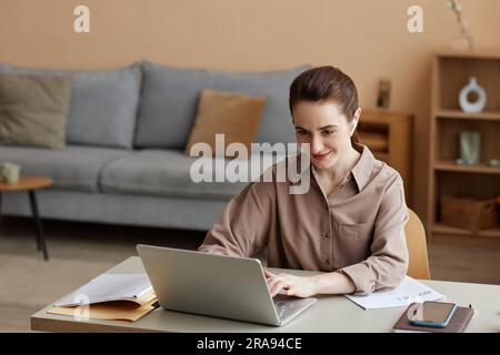 Porträt einer jungen Geschäftsfrau, die von zu Hause aus arbeitet und Laptop und Kopierraum benutzt Stockfoto