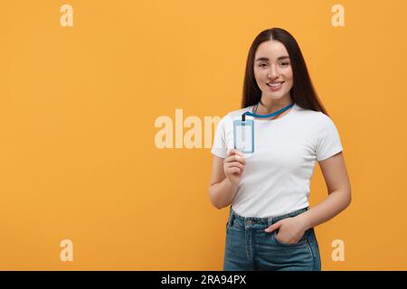 Glückliche Frau mit vip-Pass-Abzeichen auf orangefarbenem Hintergrund. Platz für Text Stockfoto