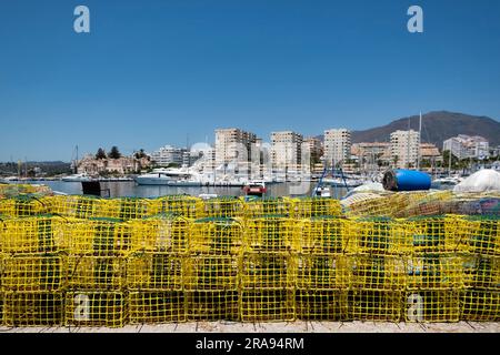 Bunte Hummertöpfe oder Krabbenkästen säumen die Seite des alten Hafens, Estepona Spanien, mit dem neuen Hafen im Hintergrund Stockfoto