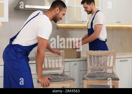 Männliche Umzugsleute mit Stühlen im neuen Haus Stockfoto