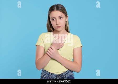 Teenager mit Schmerzen im Handgelenk auf hellblauem Hintergrund. Arthritis-Symptom Stockfoto