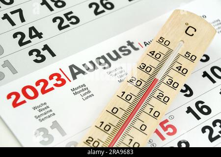 Deutscher Kalender August 2023 und Thermometer aus Holz 30 Grad Celsius Stockfoto