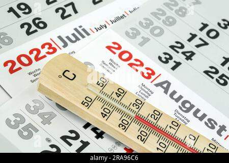 Deutscher Kalender Juli und August 2023 und Thermometer aus Holz 30 Grad Celsius Stockfoto