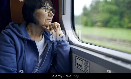 Warschau, Polen. 11. Juni 2023. Ältere Dame mit Brille reist im Zug und schaut aus dem Fenster (Kreditbild: © Andrey Nekrasov/ZUMA Press Wire), NUR REDAKTIONELLE VERWENDUNG! Nicht für den kommerziellen GEBRAUCH! Stockfoto