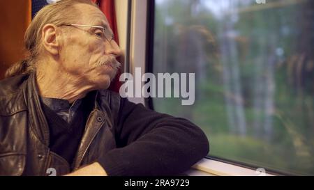 Warschau, Polen. 11. Juni 2023. Die Nahaufnahme eines älteren Mannes mit Brille reist in einem Zug und schaut aus dem Fenster (Kreditbild: © Andrey Nekrasov/ZUMA Press Wire) NUR REDAKTIONELLE VERWENDUNG! Nicht für den kommerziellen GEBRAUCH! Stockfoto