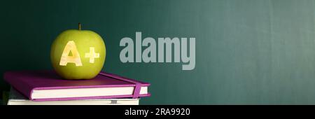 Apfel mit geschnitztem Buchstaben A und Plus als Schulklasse in Büchern nahe der grünen Tafel. Bannerdesign mit Platz für Text Stockfoto