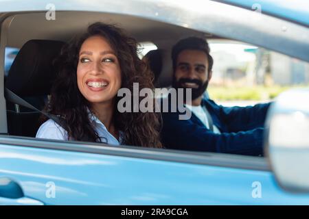 Genießen Sie das Reisekonzept. Ein lächelnder arabischer Autofahrer, eine glückliche Dame auf dem Beifahrersitz Stockfoto