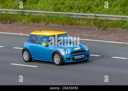 2004 Blau gelber Mini Cooper S Car Hatchback Benzinmotor 1598 cm3; Fahrt mit hoher Geschwindigkeit auf der Autobahn M6 im Großraum Manchester, Großbritannien Stockfoto