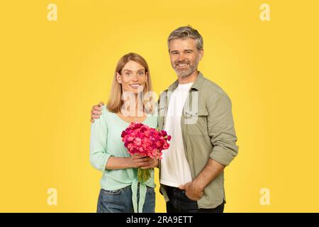 Glücklicher europäischer Ehemann mittleren Alters, der seine Frau umarmt und ihr zum Geburtstag oder Hochzeitstag gratuliert Stockfoto