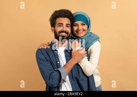 Portrait Eines Glücklichen Muslimischen Paares, Das Sich Über Beigen Hintergrund Umarmt Stockfoto