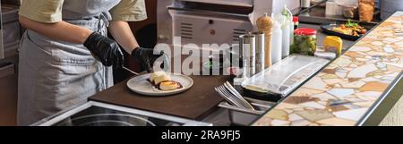 Die Chefköchin dekoriert Käsekuchen, bevor sie zum Frühstück in der Restaurantküche serviert wird Stockfoto