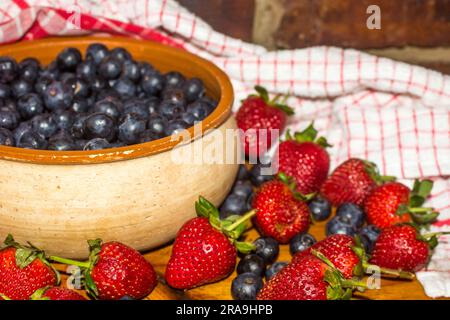 Schüssel gefüllt mit Blaubeeren, umgeben von Erdbeeren und Blaubeeren Stockfoto