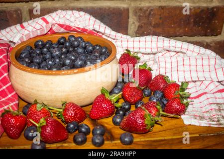 Schüssel gefüllt mit Blaubeeren, umgeben von Erdbeeren und Blaubeeren Stockfoto
