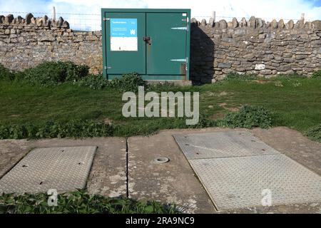 Ein großer grün lackierter Schrank neben einer trockenen Steinwand oben auf einer Klippe beherbergte elektrische Geräte, um Pumpen in einem riesigen Sumpf darunter zu betreiben. Stockfoto