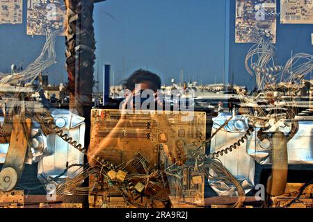 Reflexion in einem Schaufenster in einem spanischen Hafen mit antiken Kuriositäten und Fotograf, der das Foto macht, Spanien, Europa Stockfoto