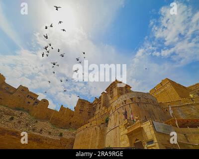 Ein riesiges und sehr impessives Fort in Indien unter dem wolkigen blauen Himmel und den Vögeln Stockfoto