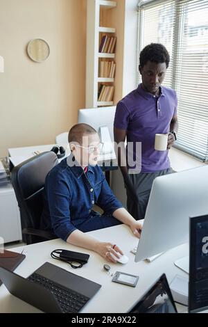 Zwei junge, ernsthafte Kollegen in der Freizeitkleidung, die während der Vorbereitung einer Präsentation oder der Arbeit an einem neuen Projekt im Büro auf den Bildschirm schauen Stockfoto