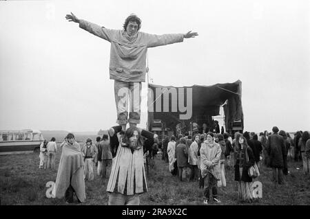 Stonehenge Free Festival bei der Sommersonnenwende am 21. Juni, Festivalbesucher, es regnet und kalt, eine Band ist auf der Bühne. Wiltshire, England, ca. Juni 1976. HOMER SYKES AUS DEN 1970ER JAHREN Stockfoto
