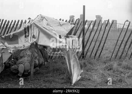 Stonehenge Free Festival bei der Sommersonnenwende, Wiltshire, England, ca. Juni 1976. Festivalbesucher versuchen, sich in ihrem provisorischen Zelt warm und trocken zu halten. 1970S GB HOMER SYKES Stockfoto