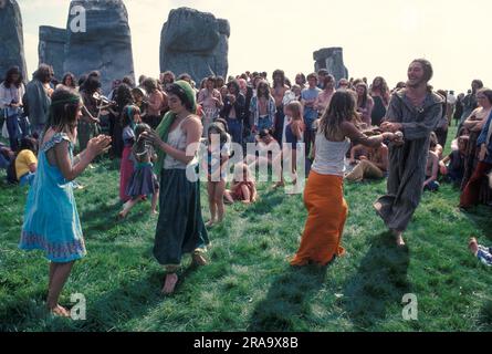 Stonehenge Free Festival zur Sommersonnenwende 1970 Eine kleine Gruppe von New Age Hippies im Stil der 1970er Jahre, eine Familiengruppe tanzen und feiern zusammen, während andere zusehen. Wiltshire, England, 21. Juni 1979. HOMER SYKES AUS DEN 70ER JAHREN Stockfoto