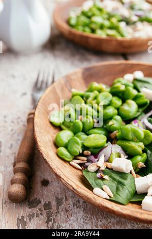 Ein frischer Salat mit geschälten Saubohnen, Baby-Blattspinat, roten Zwiebeln, Pinienkernen und zerbröckelte Soja-Käse. Stockfoto