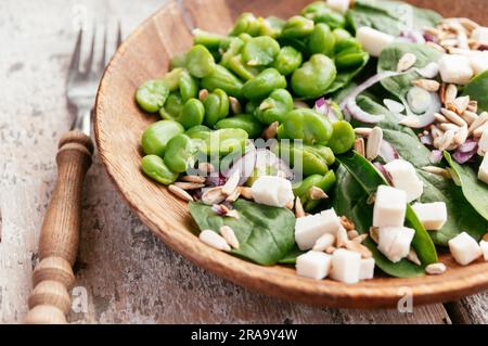 Ein frischer Salat mit geschälten Saubohnen, Baby-Blattspinat, roten Zwiebeln, Pinienkernen und zerbröckelte Soja-Käse. Stockfoto