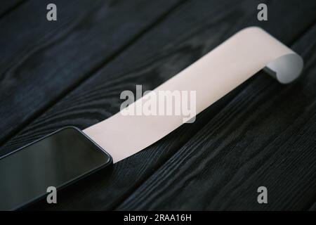 Ein Handy mit einem Blankoscheck auf einem schwarzen Holztisch, Finanzkonzept Stockfoto