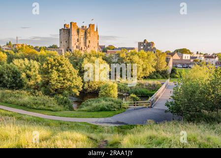 Blick über den Fluss Boyne in Richtung Trim Castle in der Grafschaft Meath, Irland, mit einer Fußgängerbrücke über dem Wasser. Stockfoto