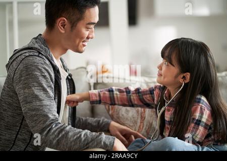 asiatischer Vater und Tochter, die zu Hause Arzt und Patient spielen Stockfoto