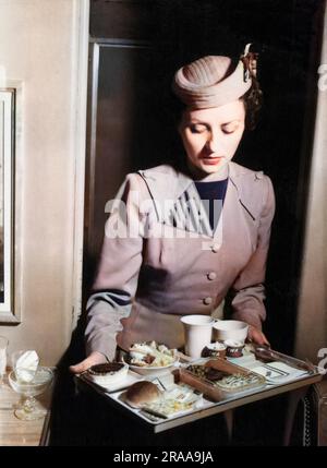 TWA (Trans World Airlines) Stewardess mit einer Mahlzeit an Bord auf einem Tablett. Datum: 1940er Stockfoto