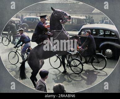 Ein berittener Polizist, der ein unerfahrenes Pferd an die Verkehrsbedingungen in London gewöhnt, rioriert an die Krönungsprozession vom 12. Mai 1937. Datum: 1937 Stockfoto