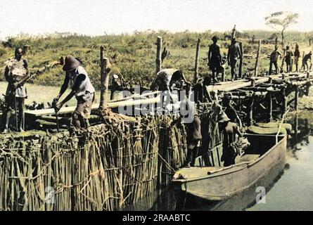 Örtliche Arbeiter bauen einen provisorischen Staudamm am Fluss Dangu im belgischen Kongo (Zaire). Der Damm wurde gebaut, um einen See zu schaffen, damit das fliegende Boot „Corsair“ starten konnte. Das Flugboot Imperial Airways hatte im März 1939 eine Zwangslandung durchgeführt und wurde zunächst als nicht reparierbar angesehen, und die Anordnung, es abzubauen, wurde erteilt. Ein Firmeningenieur aus Alexandria dachte etwas anderes, und es wurden Reparaturen durchgeführt und ein erster Damm errichtet. Der Startversuch im Juni 1939 ist gescheitert, und es kam zu weiteren Schäden. Nach weiteren Repaiern und dem Bau eines zweiten Dammes, dem SE Stockfoto